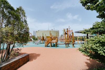 Smiling kids playing together on a safe, green outdoor playground under clear skies.