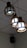 Three spherical pendant lights with wooden frames hanging from the ceiling, emitting a white glow. The ceiling is composed of white panels, and a black speaker is mounted in the corner.