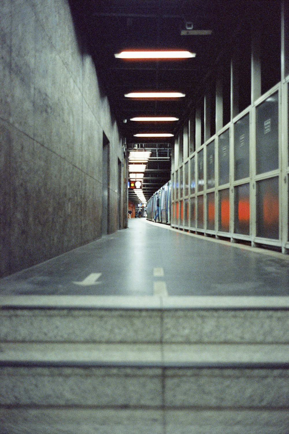 um longo corredor com piso de concreto e paredes