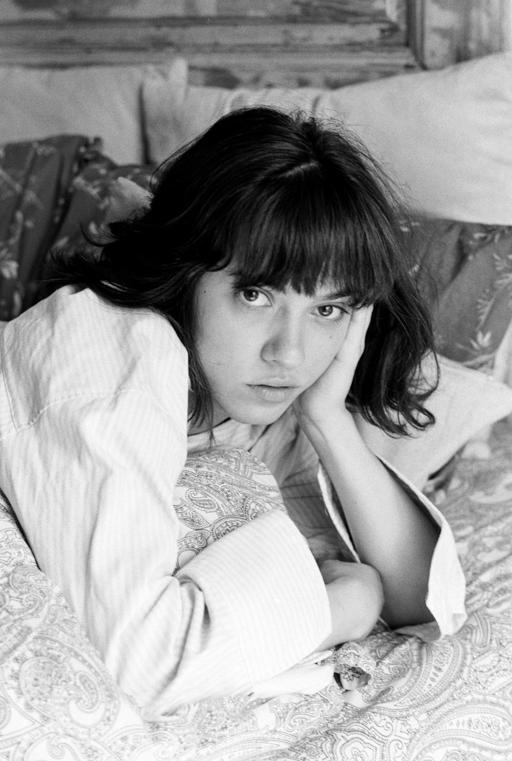 a woman laying on a bed with her hand on her head