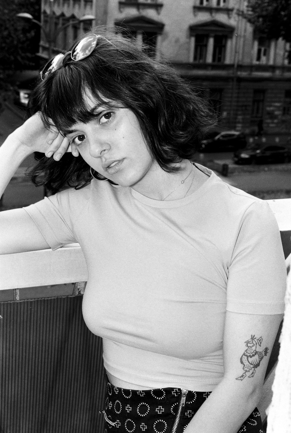 a black and white photo of a woman leaning on a fence