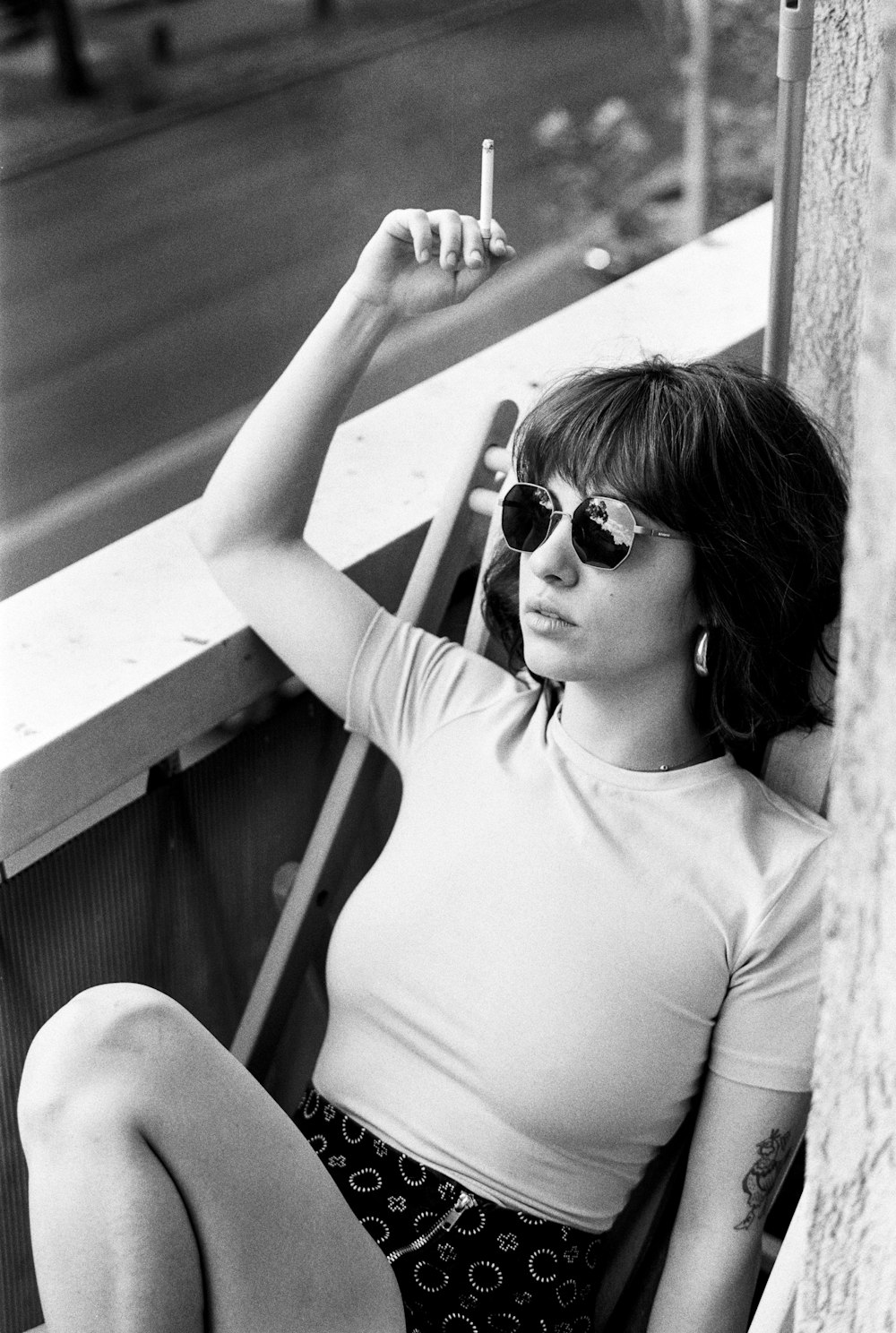a woman sitting on a ledge smoking a cigarette