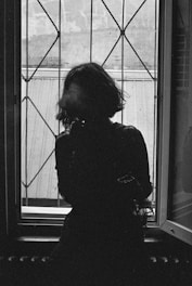 A moody black-and-white frame showing a silhouette against a window.