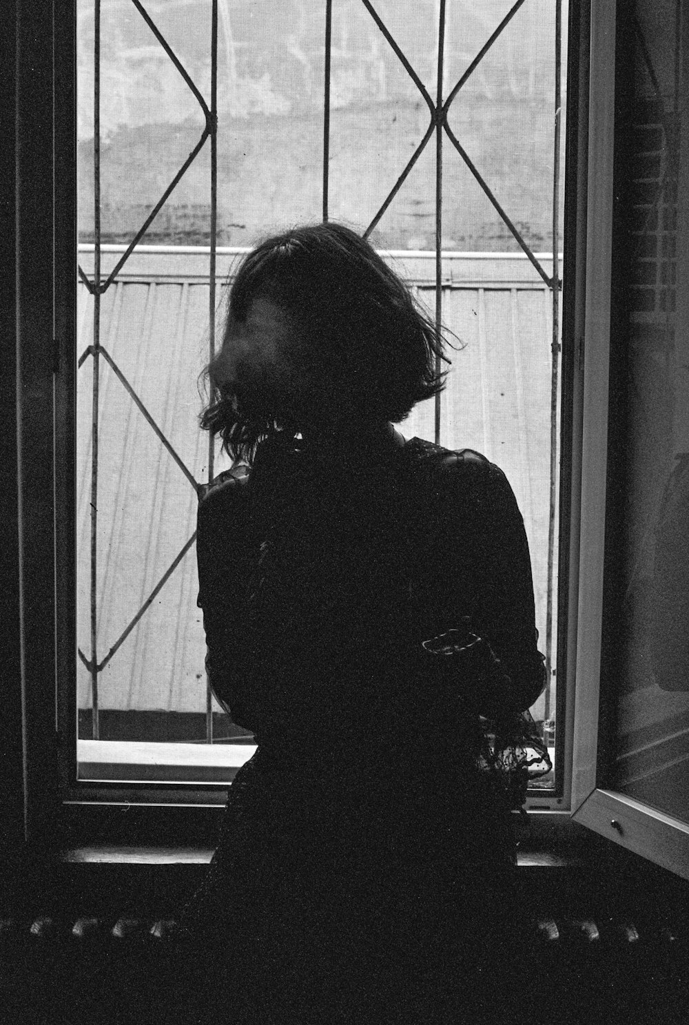 a black and white photo of a person looking out a window