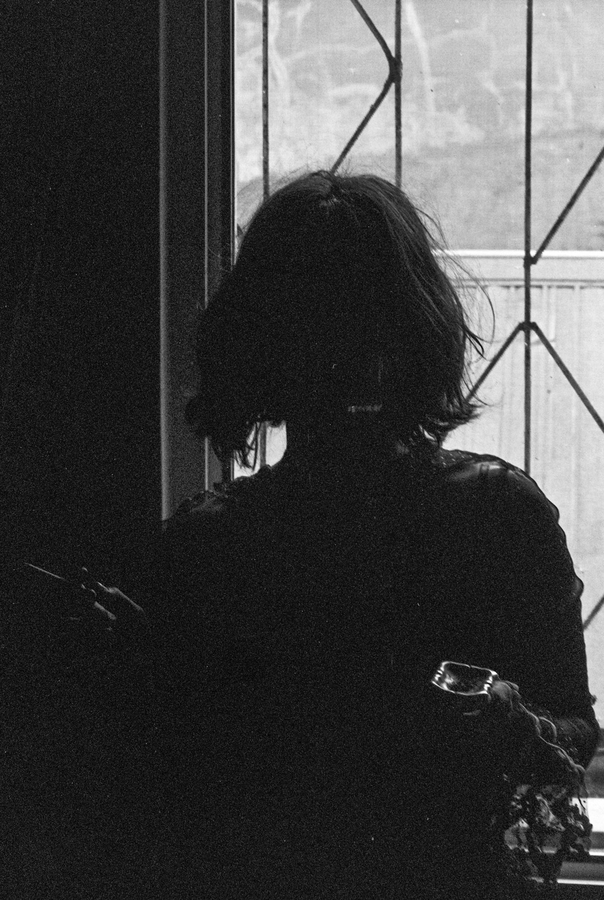 A person sitting quietly alone, silhouetted against a window