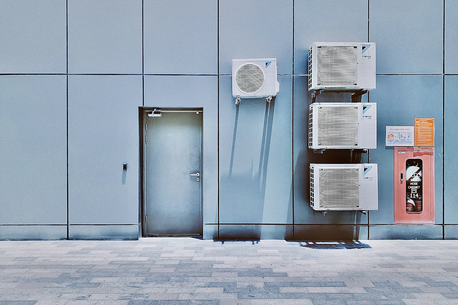 couple of air conditioners on the side of a building