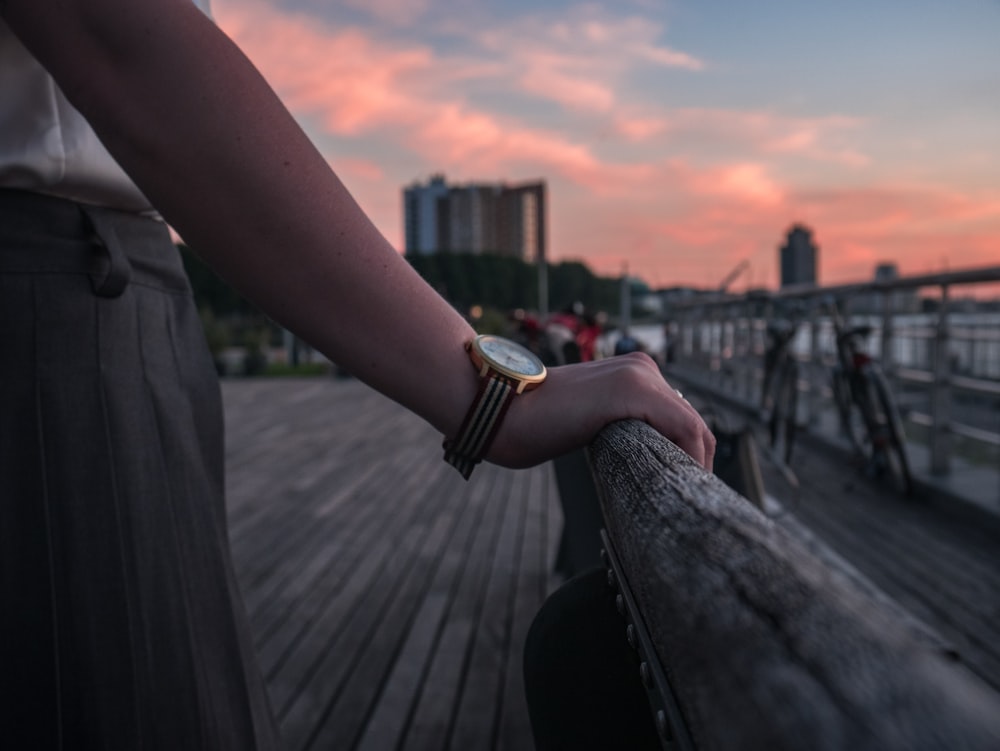 a person holding onto a wooden rail near a body of water