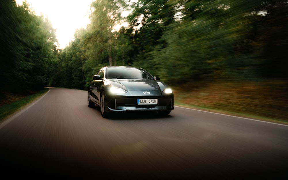 a car driving down a road with trees in the background