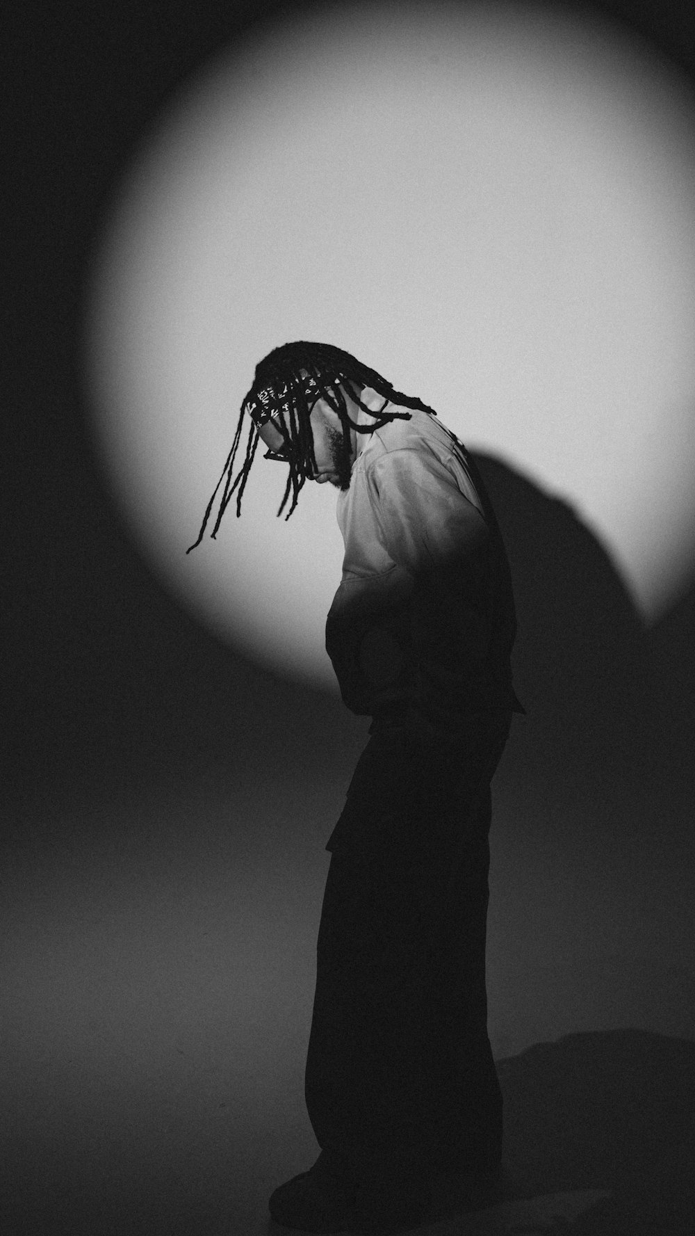 a person with dreadlocks standing in a dark room