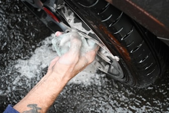 a man washing a car tire with a rag