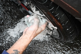 a man washing a car tire with a rag