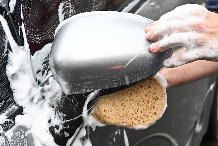 A person washing a car with a sponge