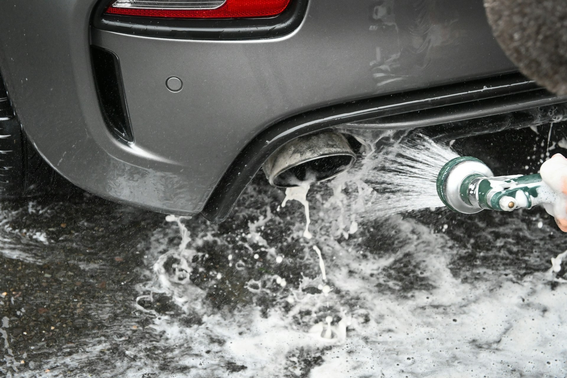 a person is washing a car with a hose