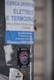 A pole displays a large advertisement for electricians and plumbers with urgent hiring needs in Italian. Below this is a colorful sticker for 'Moon Omens' featuring a stylized eye logo, alongside social media icons and web address.