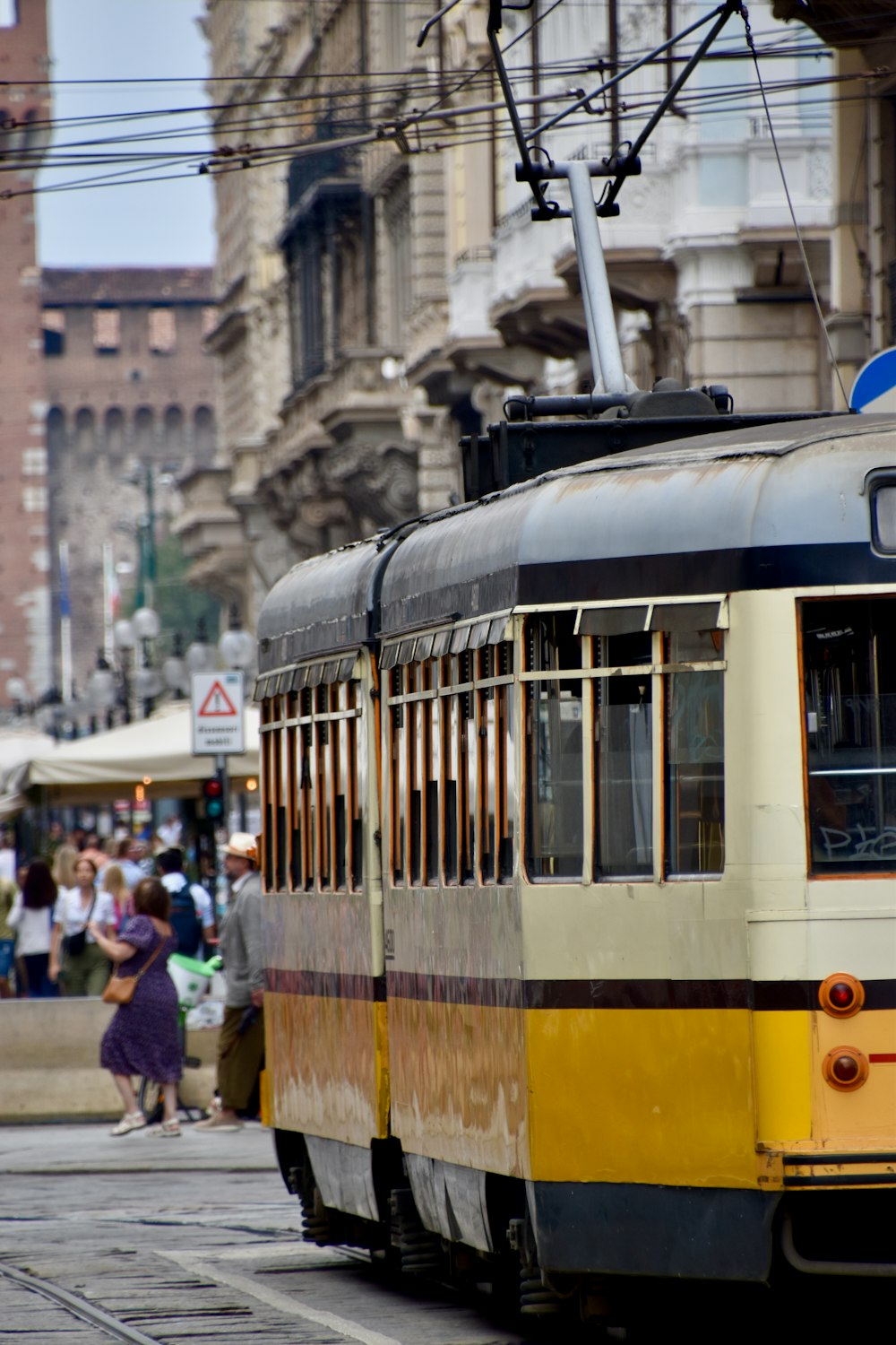 a yellow and black trolley on a city street