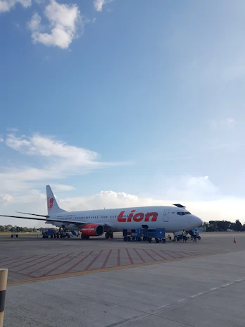 A team of ground crew in blue uniforms guiding an airplane on the tarmac under a clear sky.