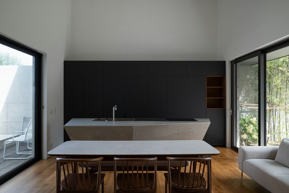 Cozinha com mesa de madeira, cadeiras e pia junto da janela