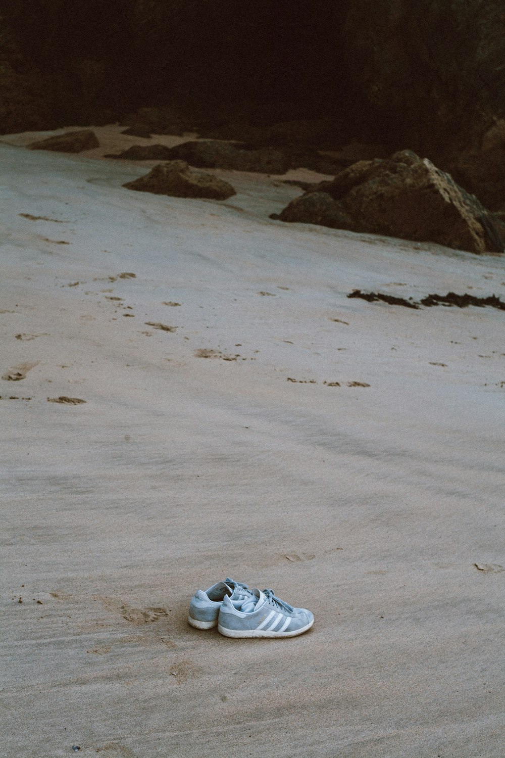 a pair of shoes sitting on top of a sandy beach