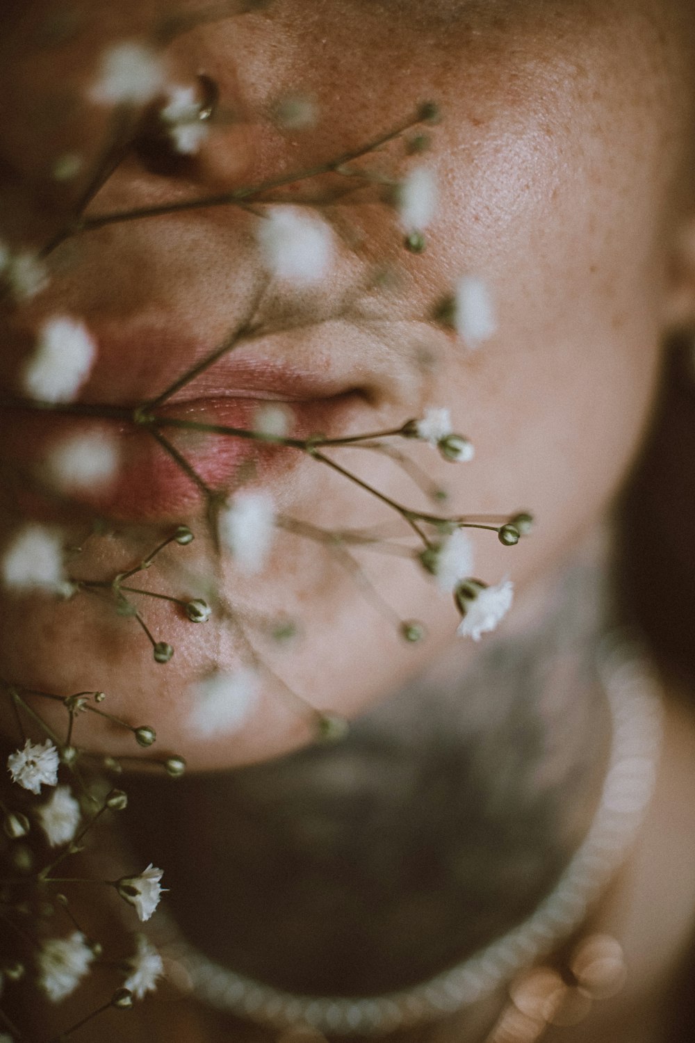a close up of a woman's face with flowers in her mouth