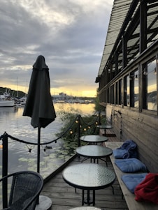 A sleek floating restaurant platform set on calm water, showcasing polished wood decking and a steel frame under a sunset sky.