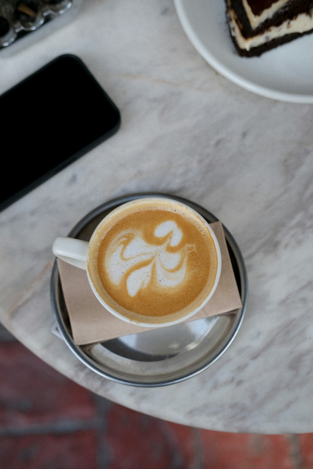 a cup of coffee on a table with a piece of cake