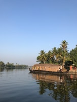 A calm houseboat floating on the reflective waters of Alleppey's backwaters at sunset.