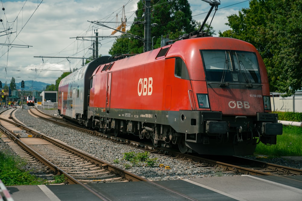 a red train traveling down train tracks next to a forest