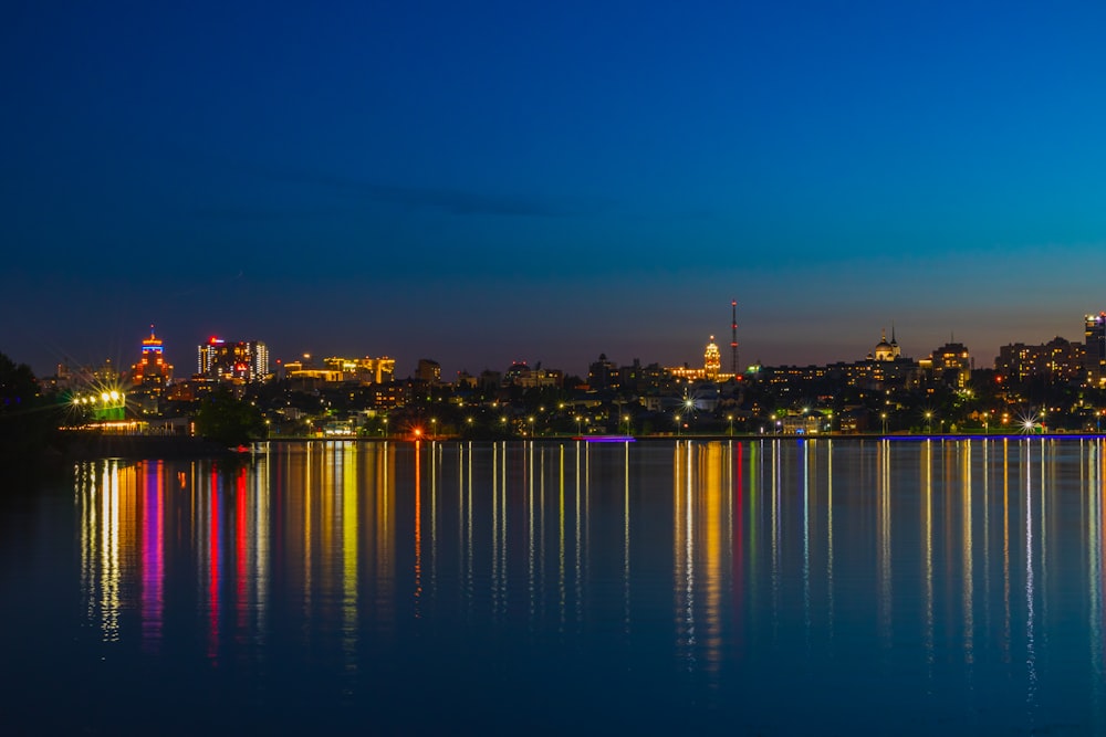 a city skyline is reflected in the water at night