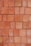 A neatly stacked arrangement of uniform red bricks arranged in a tight pattern covering the entire frame. The bricks vary slightly in hue and texture, giving the arrangement a somewhat rustic and natural appearance.