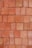 A neatly stacked arrangement of uniform red bricks arranged in a tight pattern covering the entire frame. The bricks vary slightly in hue and texture, giving the arrangement a somewhat rustic and natural appearance.