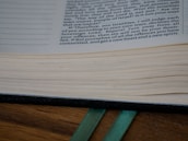 Close-up of hands holding an open book with colorful bookmarks.