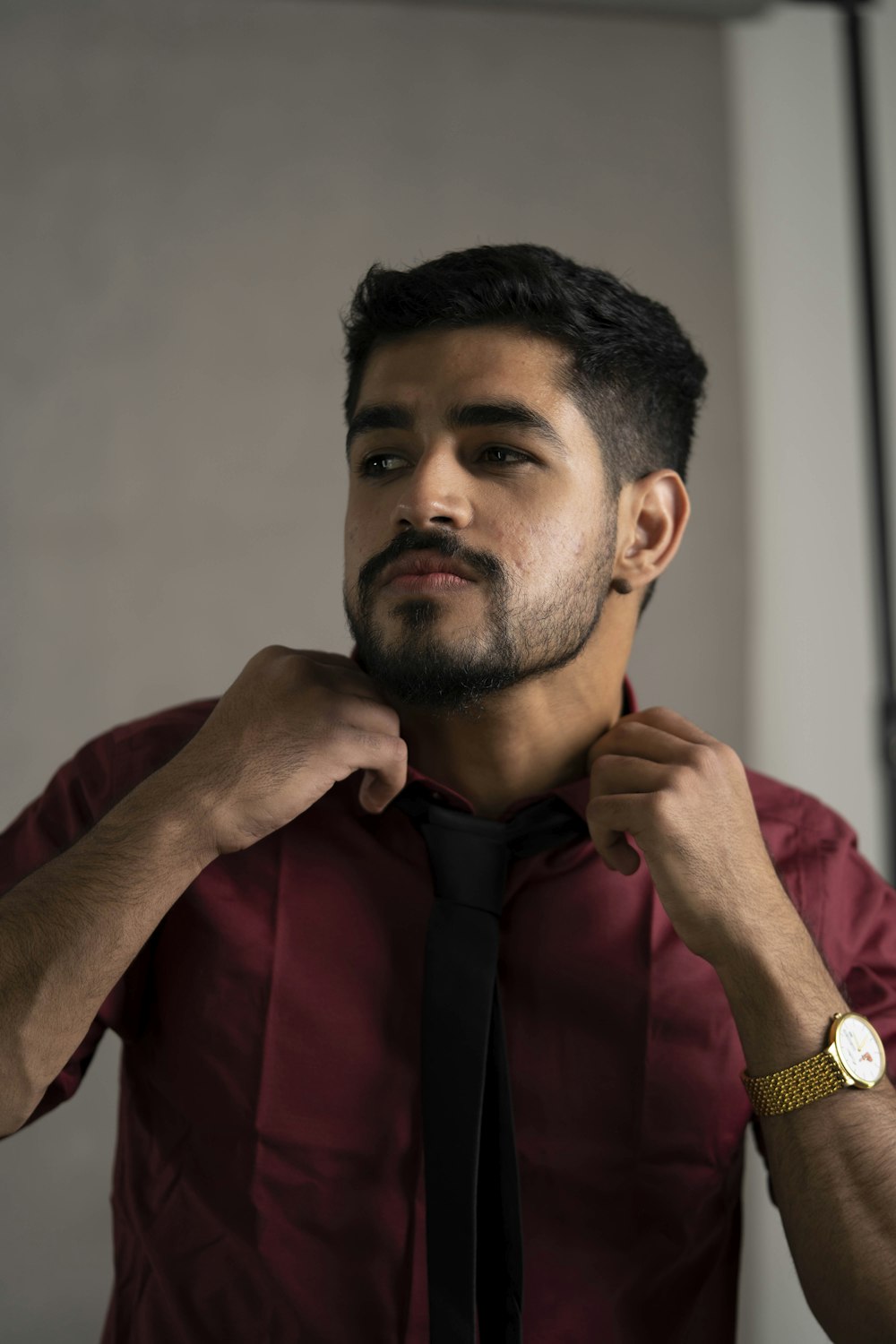 a man in a red shirt adjusting his tie