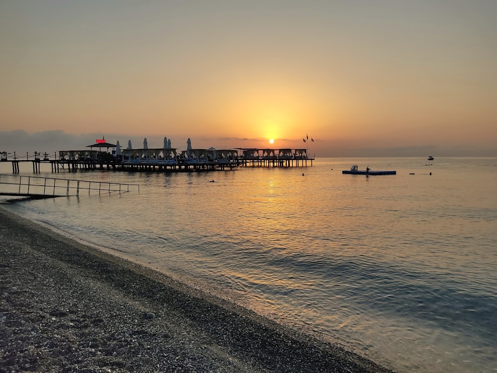 the sun is setting over the water at the beach