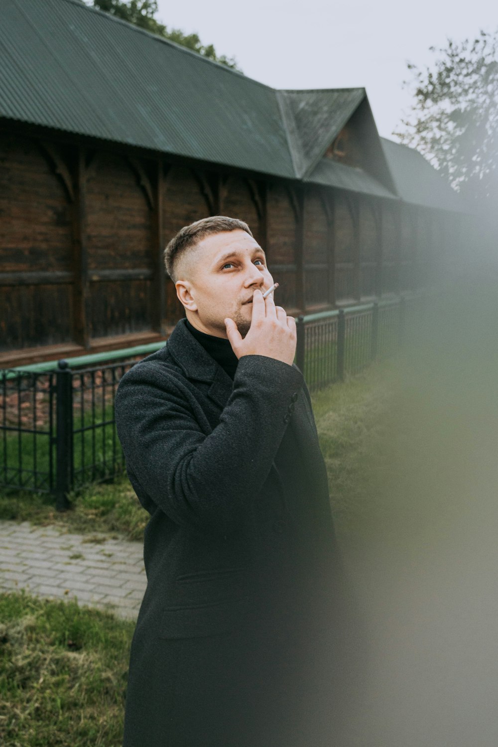 a man standing in front of a building smoking a cigarette