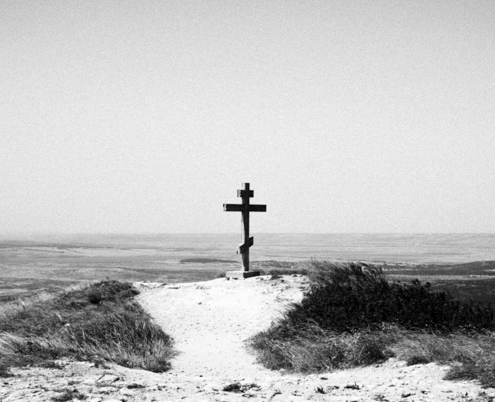 a black and white photo of a cross on a hill