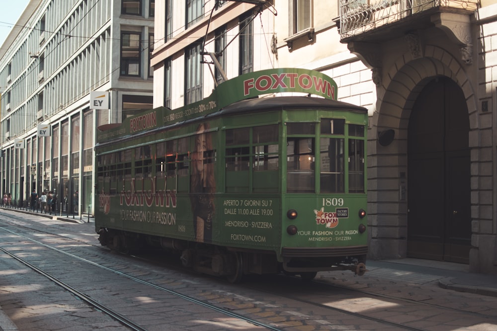 a green trolley car on a city street