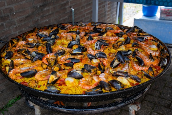 A large paella of seafood and rice on a grill