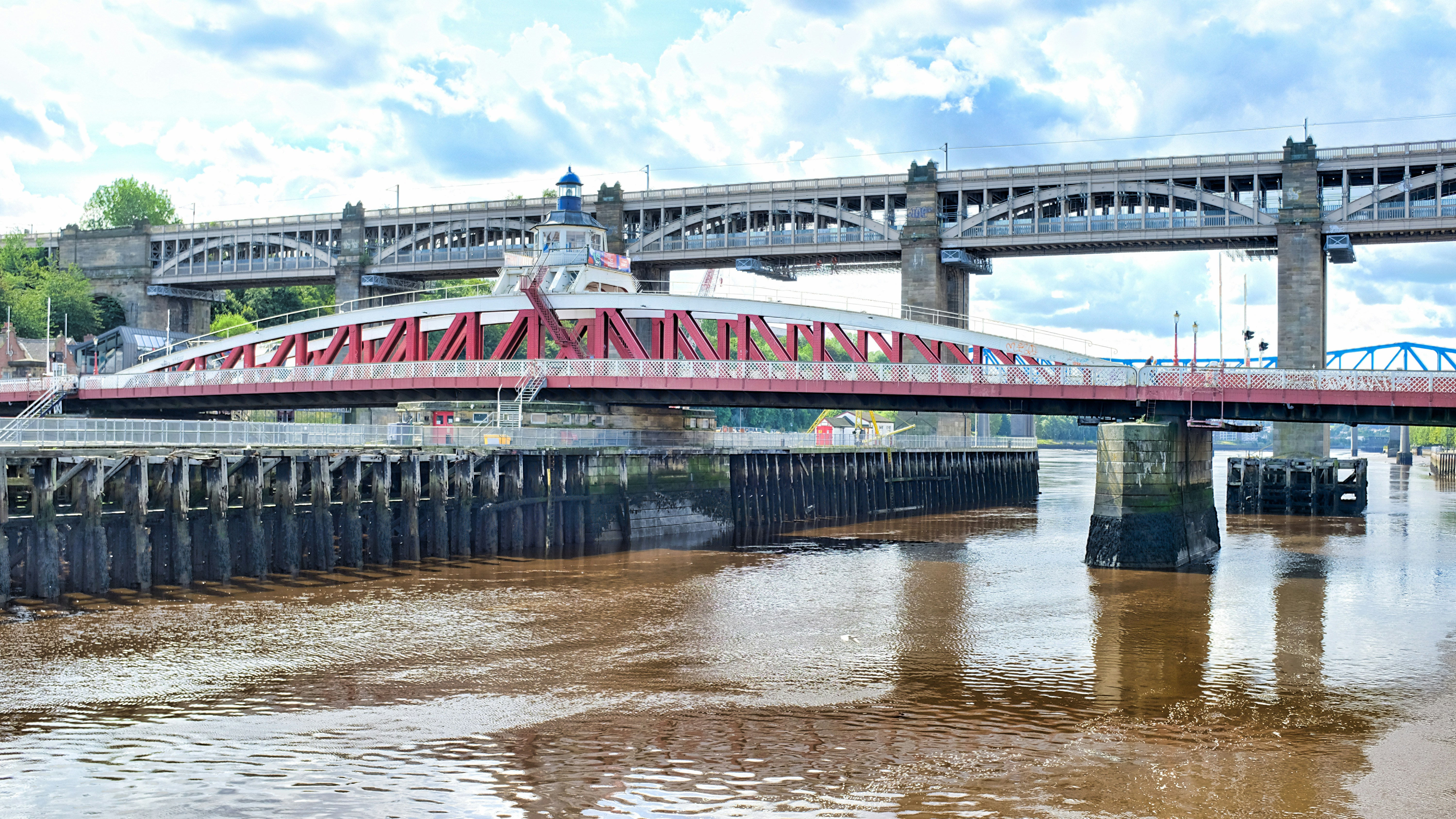 a red bridge over a river with a sky background