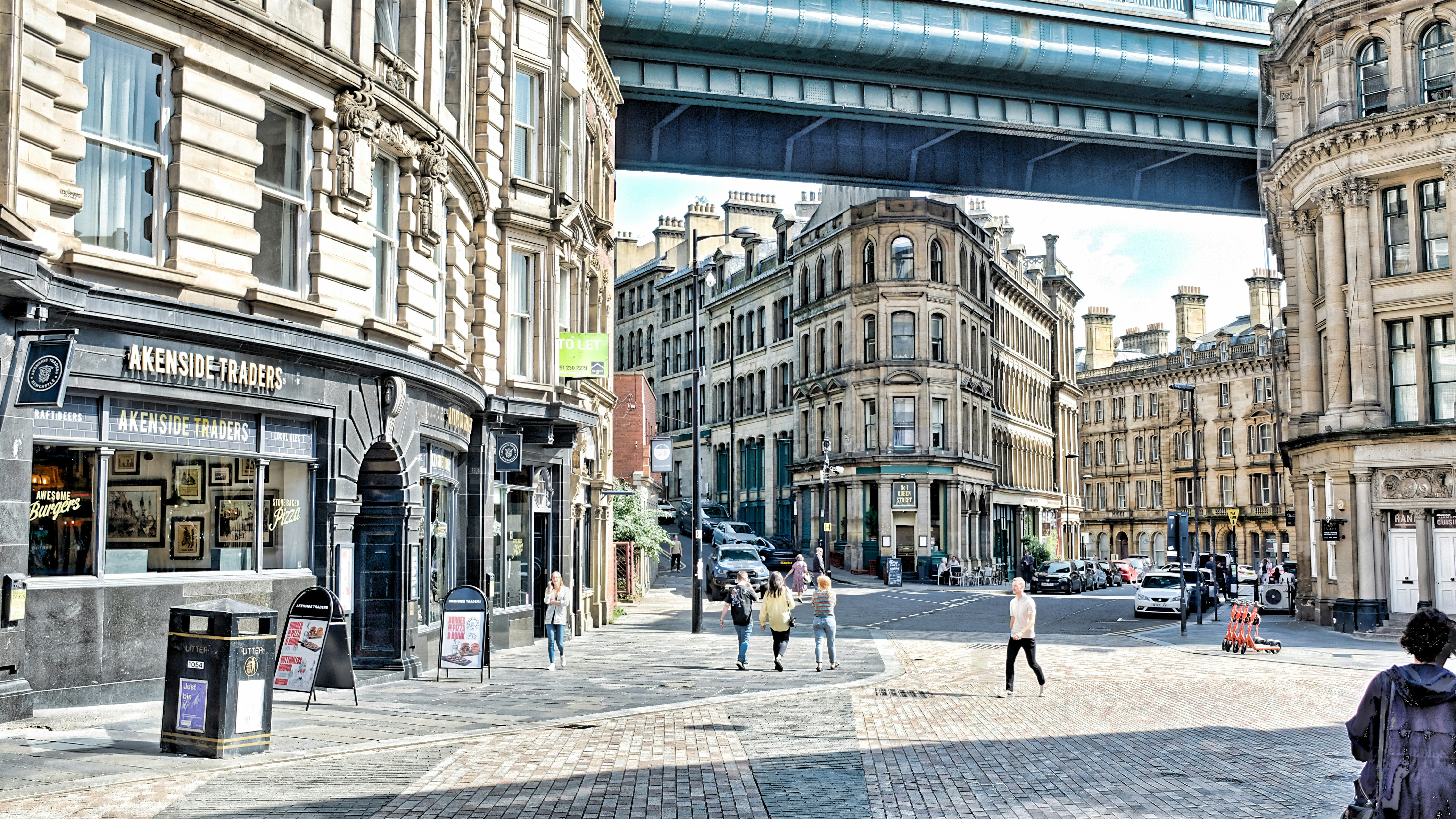 a group of people walking down a street next to tall buildings