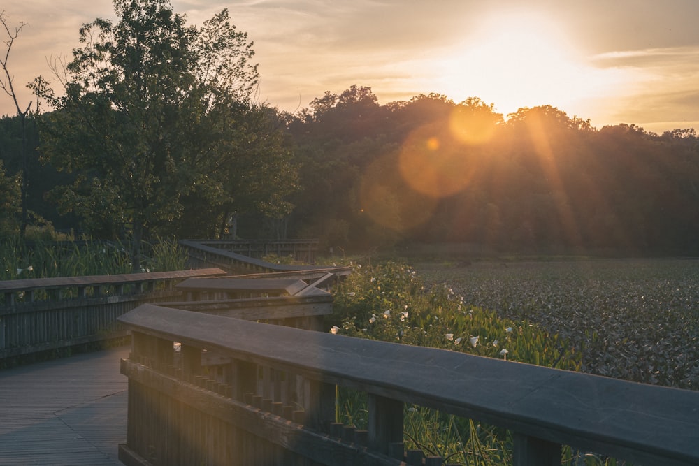 the sun is setting over a wooden bridge