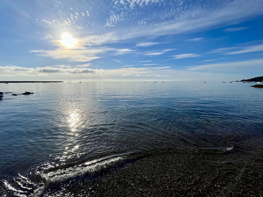 the sun is shining over the water on the beach