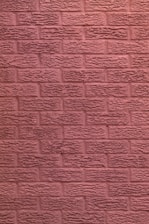 a black and white cat sitting on a red brick wall