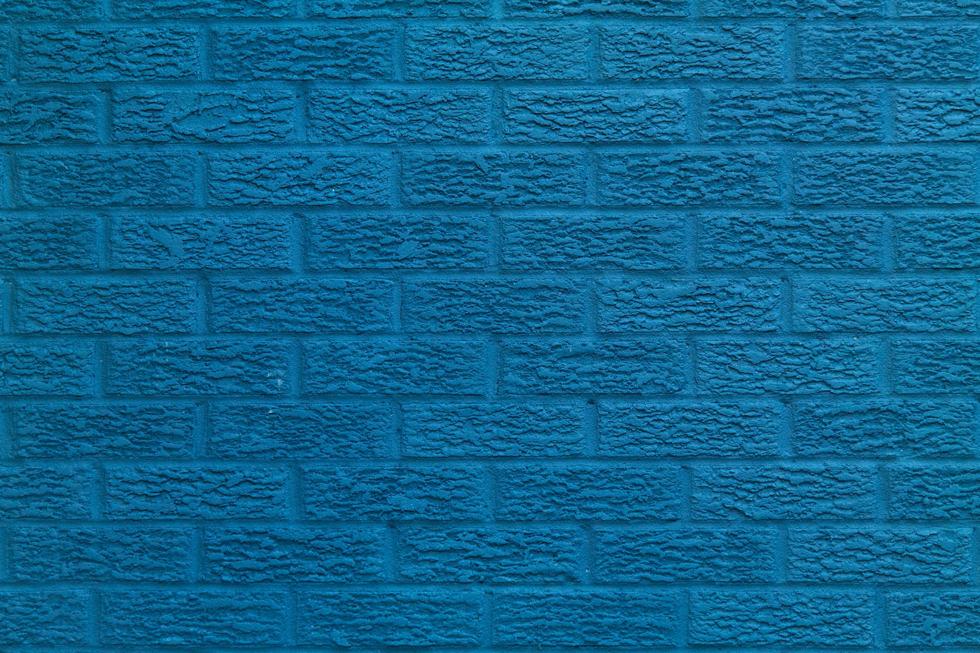 a blue brick wall with a black cat sitting on top of it