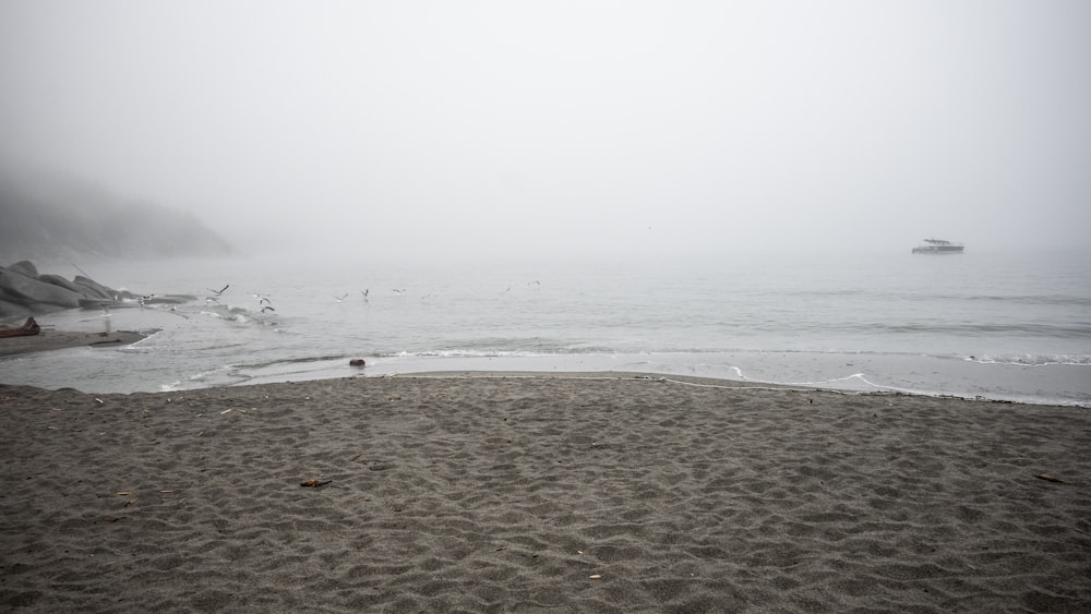 a foggy beach with a boat in the distance