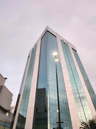 a tall glass building with a street light in front of it