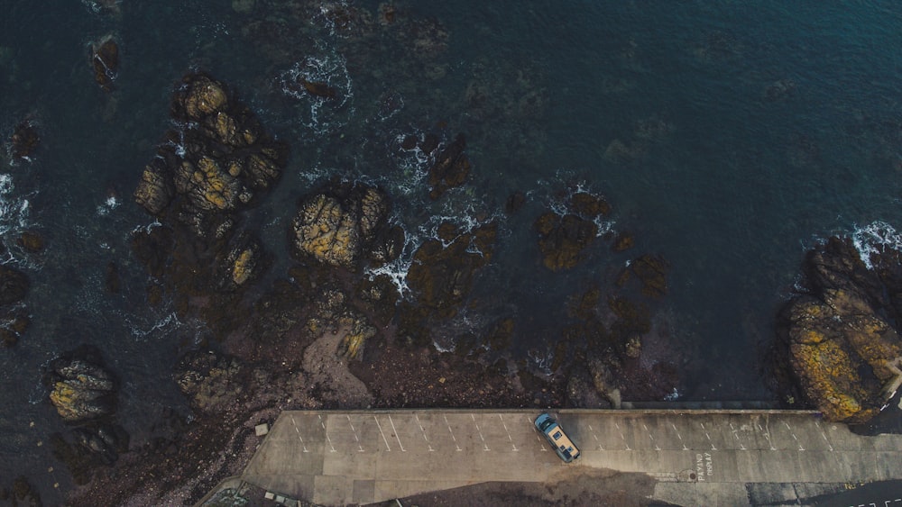 an aerial view of a car parked on a road next to the ocean