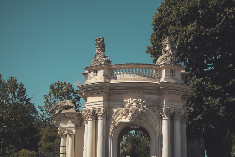 a white arch with statues on top of it