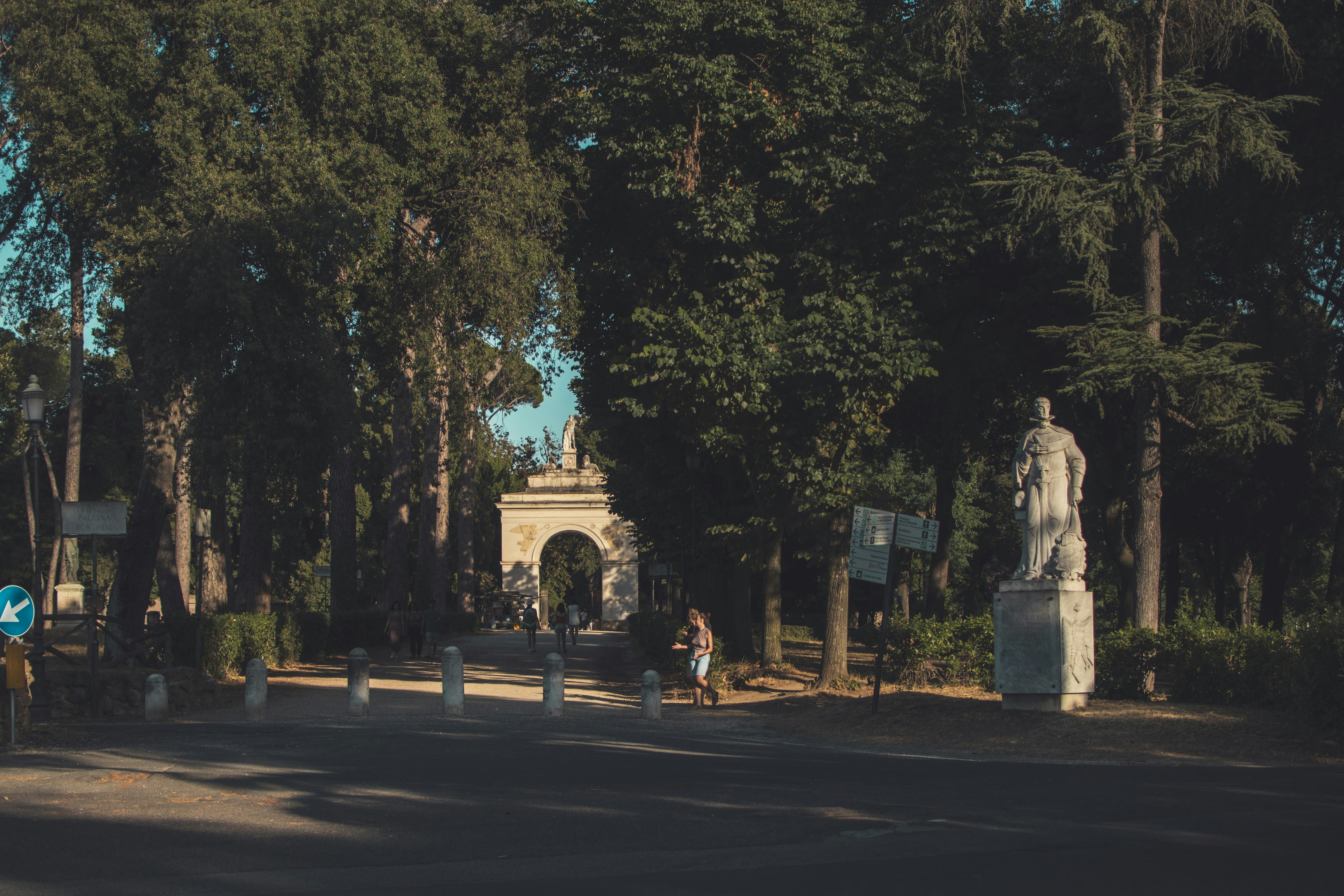 a statue in the middle of a road surrounded by trees
