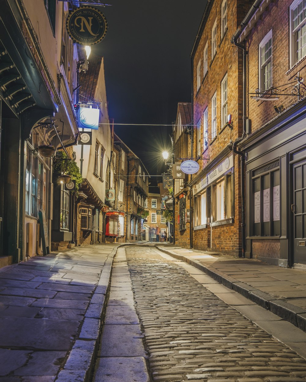 a cobblestone street at night with a clock on the building