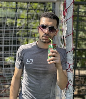 A proud parent cheering from the sidelines at a youth soccer game, holding a warm beverage.